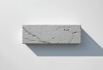 Rectangular cracked concrete block casting shadow on white surface