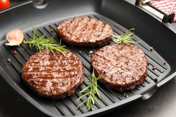Pan with grilled patties and spices on grey table, closeup