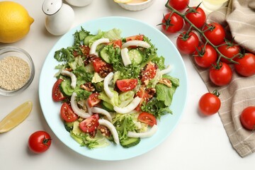 Delicious squid salad served on white table, flat lay