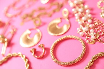 Beautiful gold jewelry on pink background, closeup