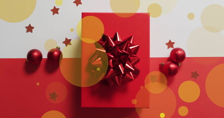 Image of yellow spots over present with christmas decorations on white and red background