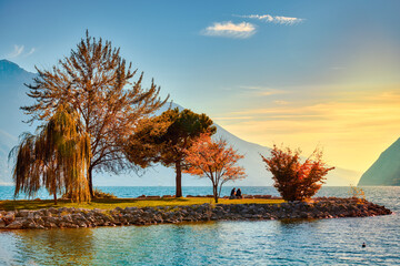 View of beautiful Lake Garda surrounded by mountains, Panoramic autumn view of sunset over Lake Garda in the evening with beautiful sunset colors, Italy