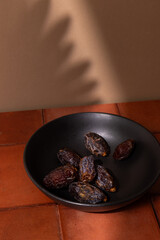 Dried Dates in a black bowl on a table, space for text