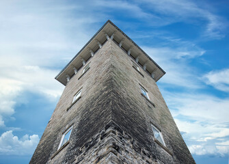 Dramatic view up of an old limestone tower and the sky above, reflections in windows, daytime, nobody