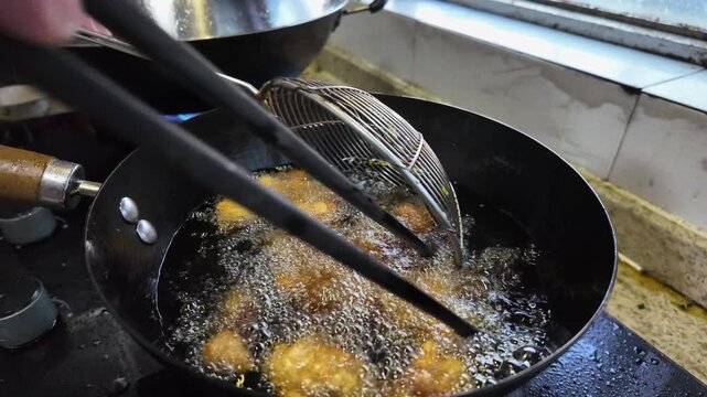 Slow motion of a chef frying chicken nuggets in a frying pan
