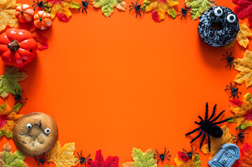 Cute donut and cookie put on orange background with halloween decorations and maple leaves for Halloween holiday concept.