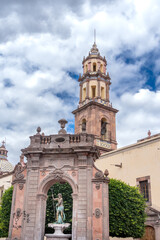 Obraz premium A beautiful building with a tall tower and a fountain in front of it. Historic center of Querétaro, colonial architecture, decorations for the celebration of Mexico's Independence Day.