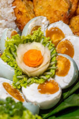 Close-up of traditional Indonesian salted duck eggs, sliced and served with rice, fresh vegetables, and decorative garnish