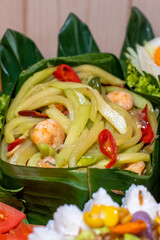 Authentic Indonesian dish, stir fried luffa gourd with shrimp and chili, served in banana leaf container. Traditional Asian cuisine.
