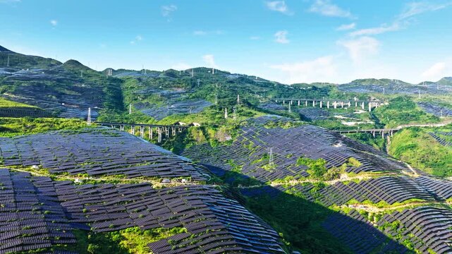 Aerial shot of a large solar panels covering the green mountain slopes, generating clean and renewable electricity.