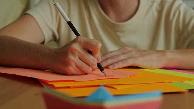 Close up footage of female hand with graphite pencil drawing on piece of colorful paper.