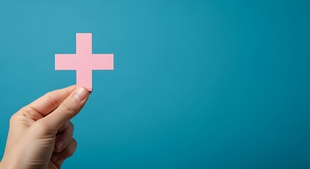 Obraz premium Hand holding a pink plus sign symbol against a teal blue background, representing addition or positive concepts