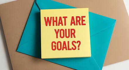 Yellow notepad asks what are your goals sitting on blue envelope