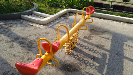 Yellow and red seesaw in public park playground. Playground equipment