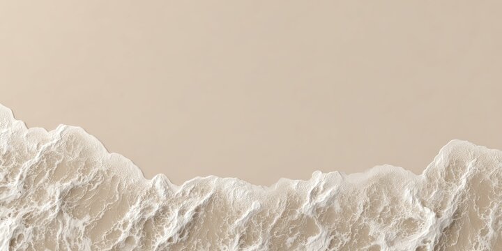 Aerial view of a beach light sand meets frothy, white surf. Soft color palette
