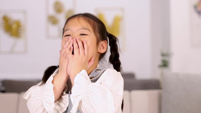 Shy Asian Girl Smiling and Covering Face Indoors