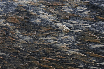 Rugged close up of natural stone texture background. This abstract pattern with gray, brown, and black tones shows detail of geology and rough material surface