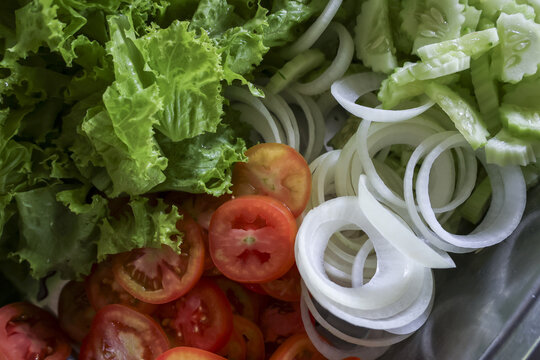 Fresh food and vegetable preparation for healthy salad. Raw sliced tomato and onion with green lettuce make an appetizing meal for healthy diet and lifestyle