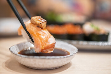 Sushi in chopsticks dipping with soy sauce