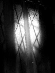 Sunlight through diamond-paned window in black and white.