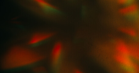 Crystal leak. Blur color background. Orange green rainbow glare shadow gleam reflection on warm art illuminated dark black abstraction.
