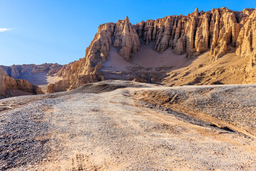 Gravel road and spectacular yardang landform mountain scenery in the desert. Famous natural landscape in Xinjiang, China.