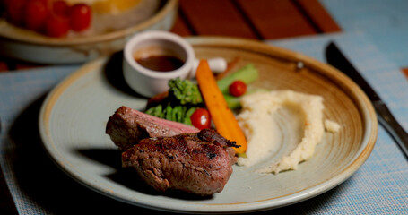 Gourmet steak dinner plate with mashed potatoes, carrots, broccoli, cherry tomatoes, and sauce. Elegant dining setting. Perfect for food photography, culinary arts.