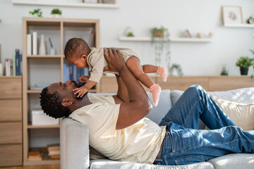 Happy african american father playing with baby at home, family love concept, parenting moments full of joy and care, father day and childhood connection, baby wellness and child insurance support