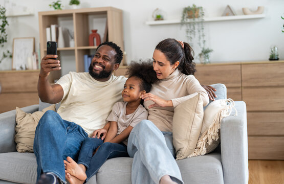 African love family spending quality time together, father holding technology smartphone watching entertainment, social media, movie or cartoon with mother and daughter, digital, relaxation at home