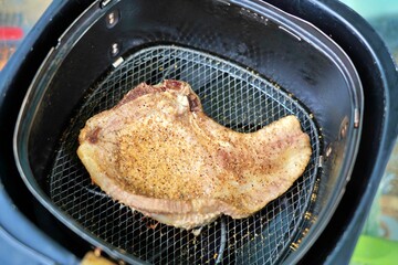 Cooked seasoned pork chop inside an air fryer basket