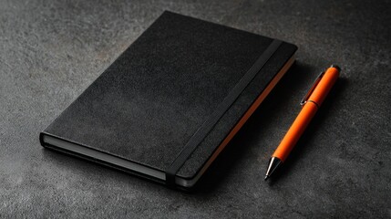 Elegant Black Notebook with Orange Pen on Dark Textured Surface