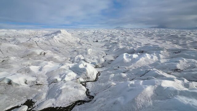 Low flyover of frozen lake on barren, sunny arctic Greenland glacier
