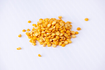 Close-up of raw yellow split peas isolated on a white background. Healthy, nutritious lentil or Bengal gram (Chana Dal) used in vegetarian and vegan cooking. Protein-rich whole food ingredient.