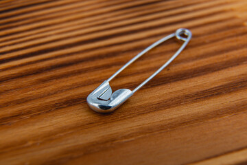 Unique silver safety pin resting on a wooden surface in natural light