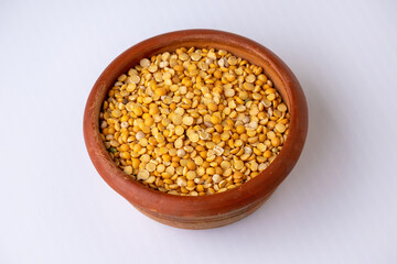 Close-up of raw yellow split peas (Chana Dal or Bengal gram) in a rustic clay bowl. Healthy whole pulse legume, nutritious ingredient for vegan cooking, curry, or soup.