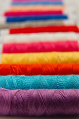 Colorful spools of thread arranged in vibrant stripes on a table