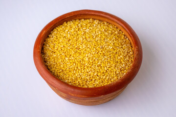 Raw, dried Moong Dal, also known as Mung Beans, in a natural earthenware bowl. Wholesome ingredient for dhal, curry, or savory snacks. Vegan, nutritious pulse.