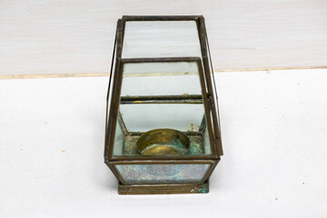 Close-up of a vintage antique brass taper candle holder with glass hurricane chimney. Elegant decorative object, traditional home decor, and historical interior design element.