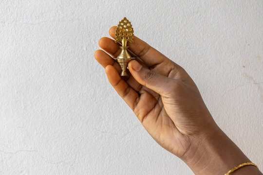 Close-up of a female hand holding an ornate Antique Brass Surmadani (Kohl or Kajal holder). Traditional cosmetic eyeliner container. Ethnic makeup and cultural beauty tool concept.