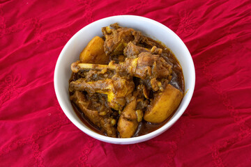 Spicy country Chicken Bhuna curry in a white ceramic bowl. Delicious homemade Indian, Pakistani, or Bangladeshi cuisine. Close-up of a rich, tasty non-vegetarian dish.