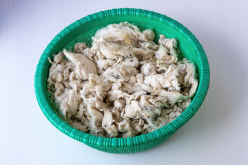 Raw Kapok fiber (Shimul tula or Bombax ceiba) in a plastic basket. Soft, white, natural silk cotton used as eco-friendly, hypoallergenic filling for pillows, bedding, and cushions.