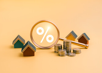 Property tax and investment concept with wooden house models, stacked coins, and magnifying glass...