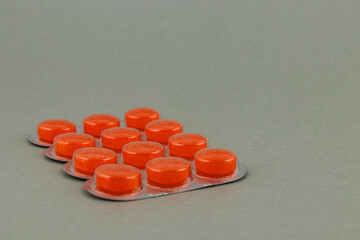 Bright orange tablets arranged neatly on a grey surface in a clinical setting