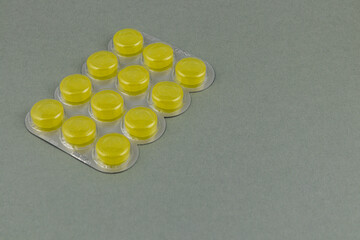 Yellow tablets arranged on a plastic blister pack on a plain surface