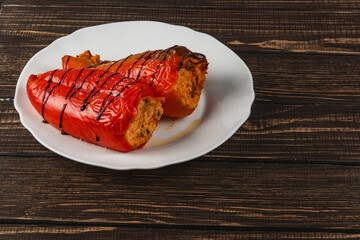 Stuffed red peppers served on a white plate on a wooden table