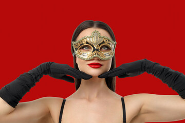 Woman in mask strikes a stylish pose against red backdrop