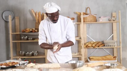 Professional male baker cutting raw dough with knife to make croissants or buns. High quality 4k footage
