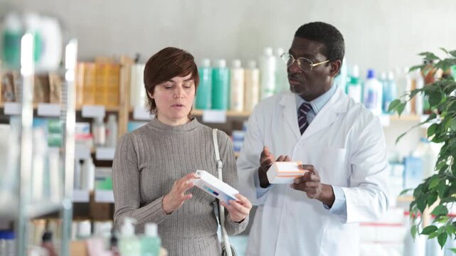 Adult woman buyer scanning qr code for ointment with adult man pharmacist in pharmacy