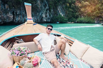 Happy man tourist in private longtail boat trip to koh Hong lagoon island at Krabi, Thailand....