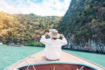 Happy Woman tourist in private longtail boat trip to koh Hong lagoon island at Krabi, Thailand....